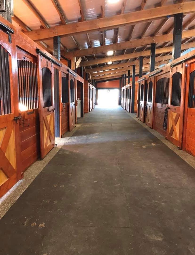 Barn aisle with richly finished wood stall doors at Off Broadway Farm