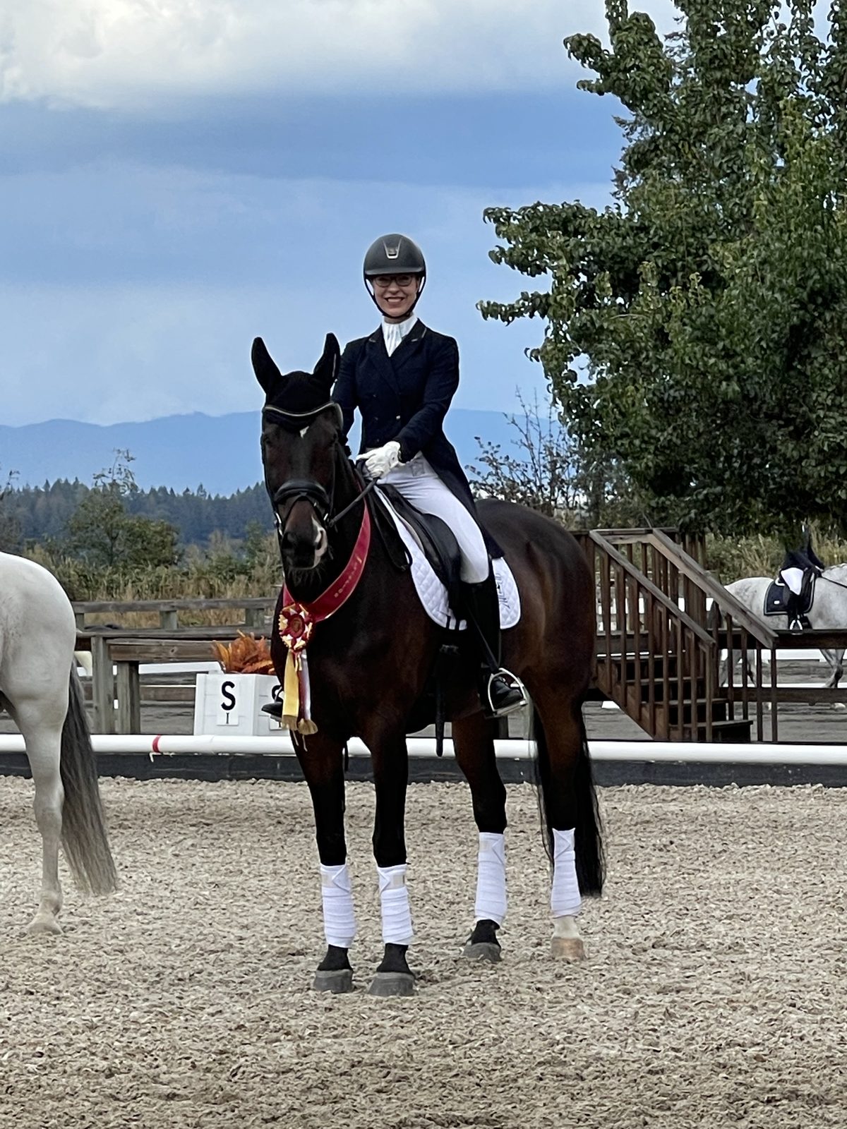 Ashley in show attire on her dark bay horse wearing a championship ribbon